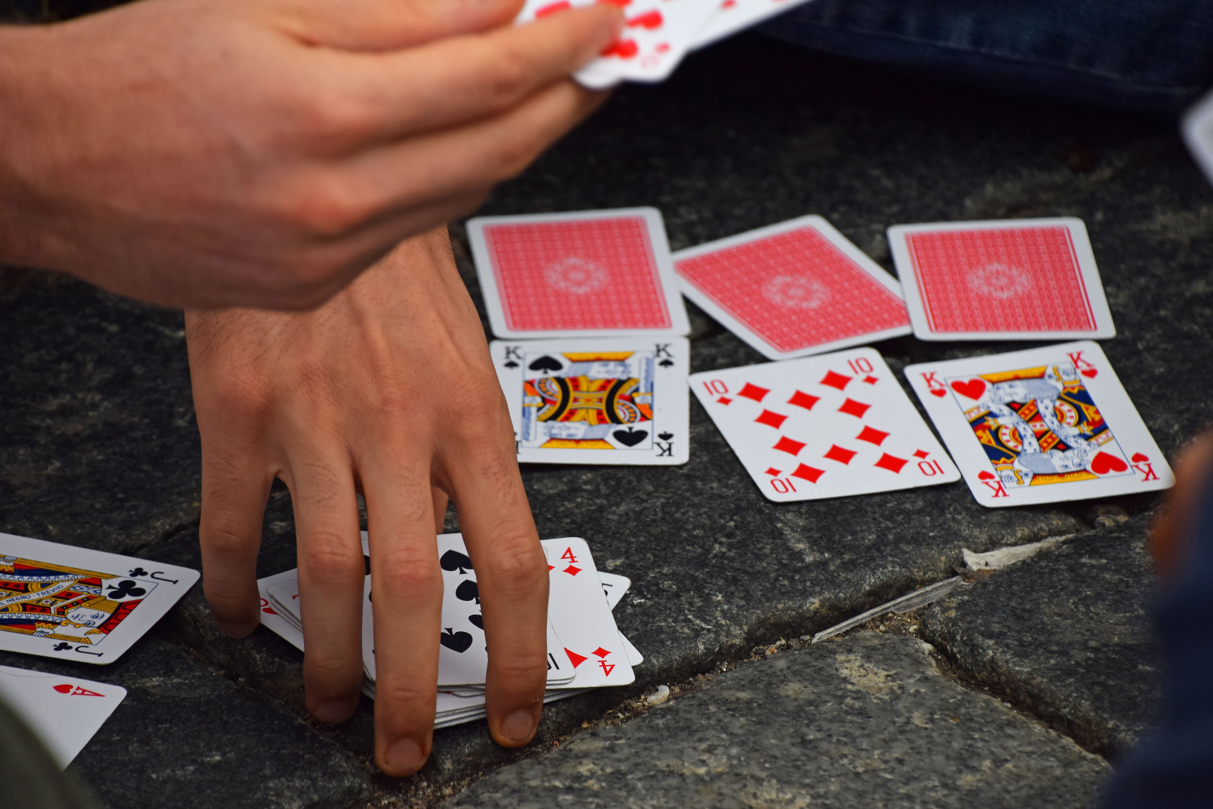 hands moving playing cards on the street pavement